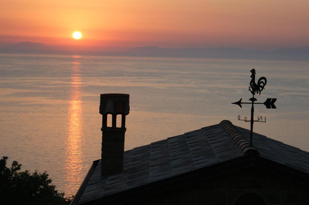 a sunset behind a building with a weather vane at Bellezza In Cilento Panoramic Apts in Castellabate