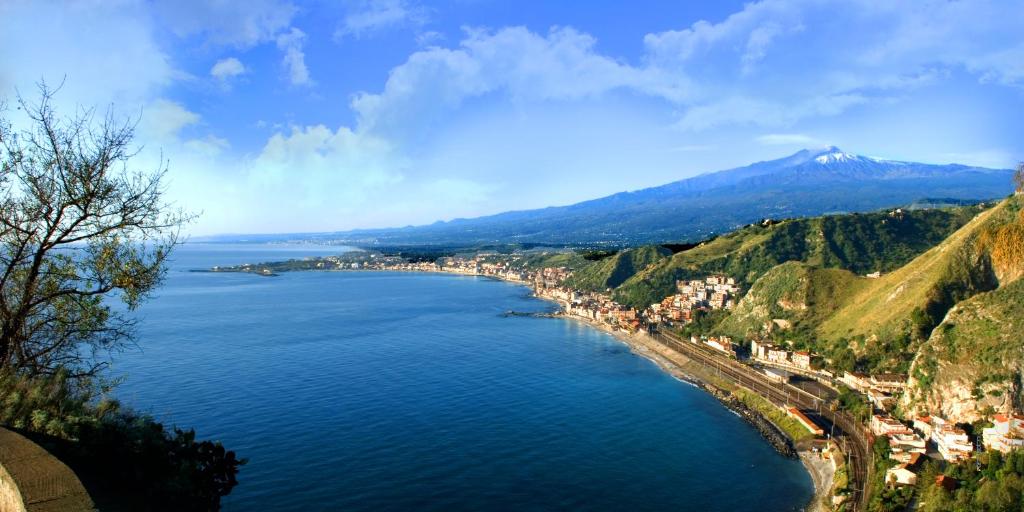 duży zbiornik wody z miastem i górami w obiekcie Taormina holidays w mieście Giardini Naxos