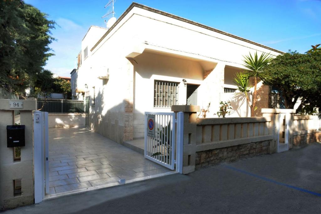 une maison blanche avec un portail et une clôture dans l'établissement Elis...land..., à Torre Canne
