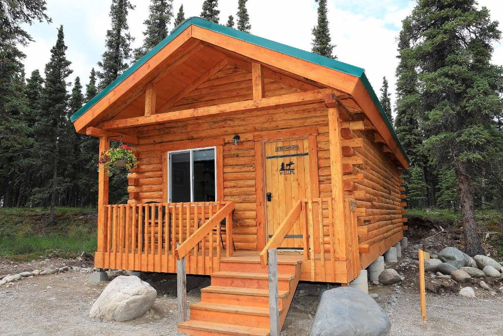 a wooden cabin with a staircase leading to the door at Denali Tri-Valley Cabins in Healy