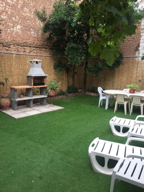 a backyard with tables and chairs and a grill at Alojamiento Turístico Las Catonas de Antoñanzas in Rincón de Soto