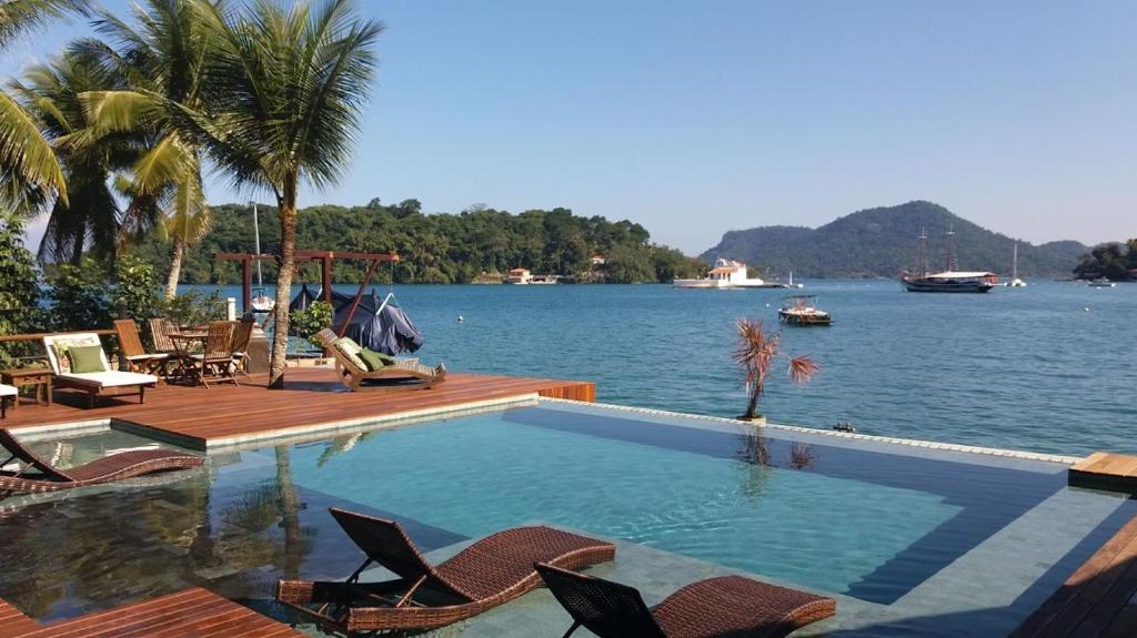 a swimming pool with chairs and a view of a lake at Pousada e Mergulho Jamanta in Angra dos Reis