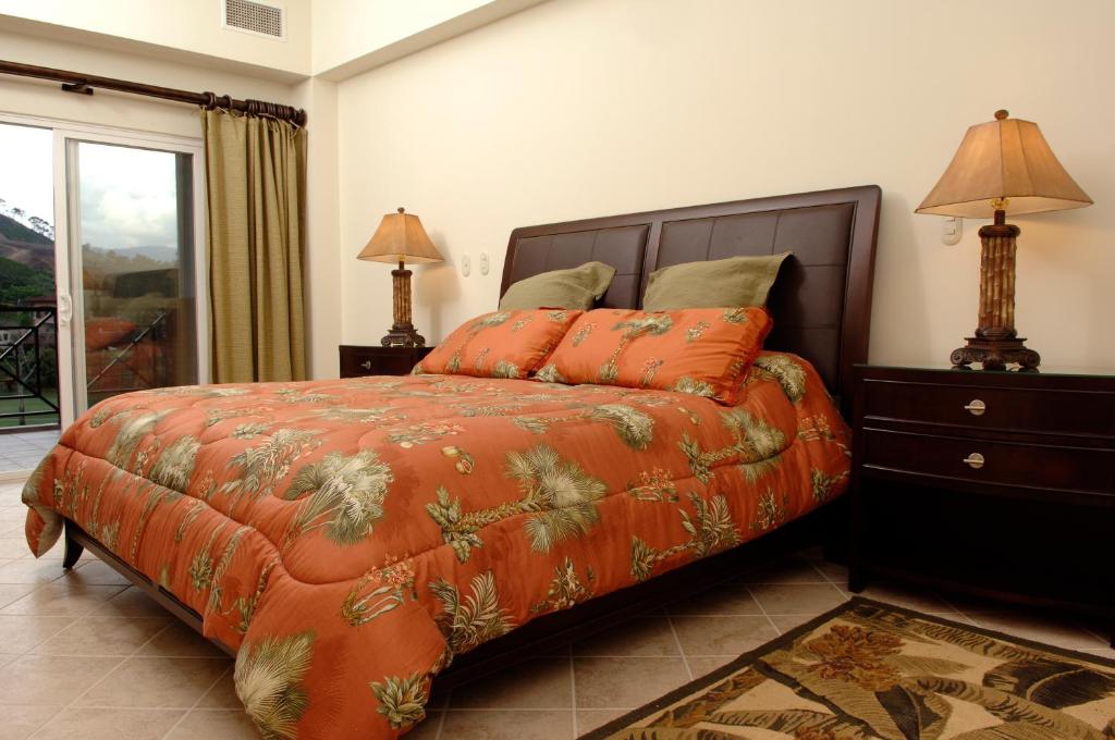 a bedroom with a bed with an orange comforter at Los Suenos Resort Veranda 6C by Stay in CR in Herradura