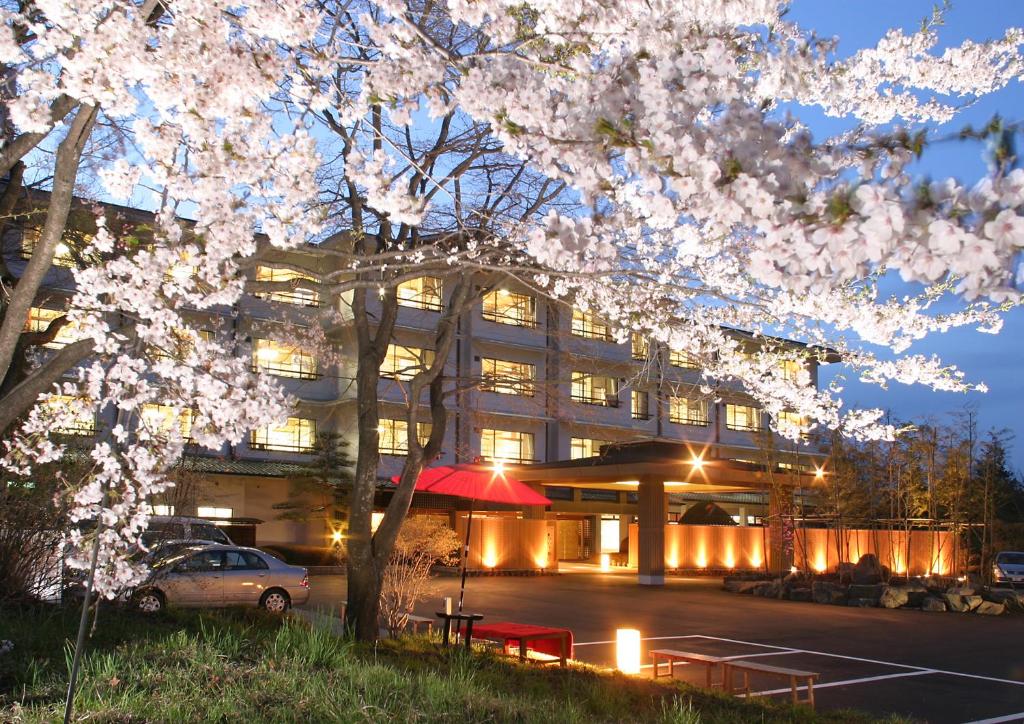 um edifício com uma árvore florida à sua frente em Joshinnosato Hibikino em Shibukawa
