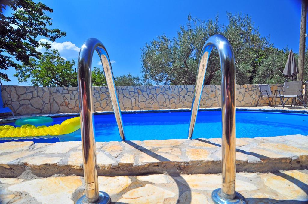 a swimming pool with two metal hand rails next to a swimming pool at Holiday Home Casa Bianca in Malinska