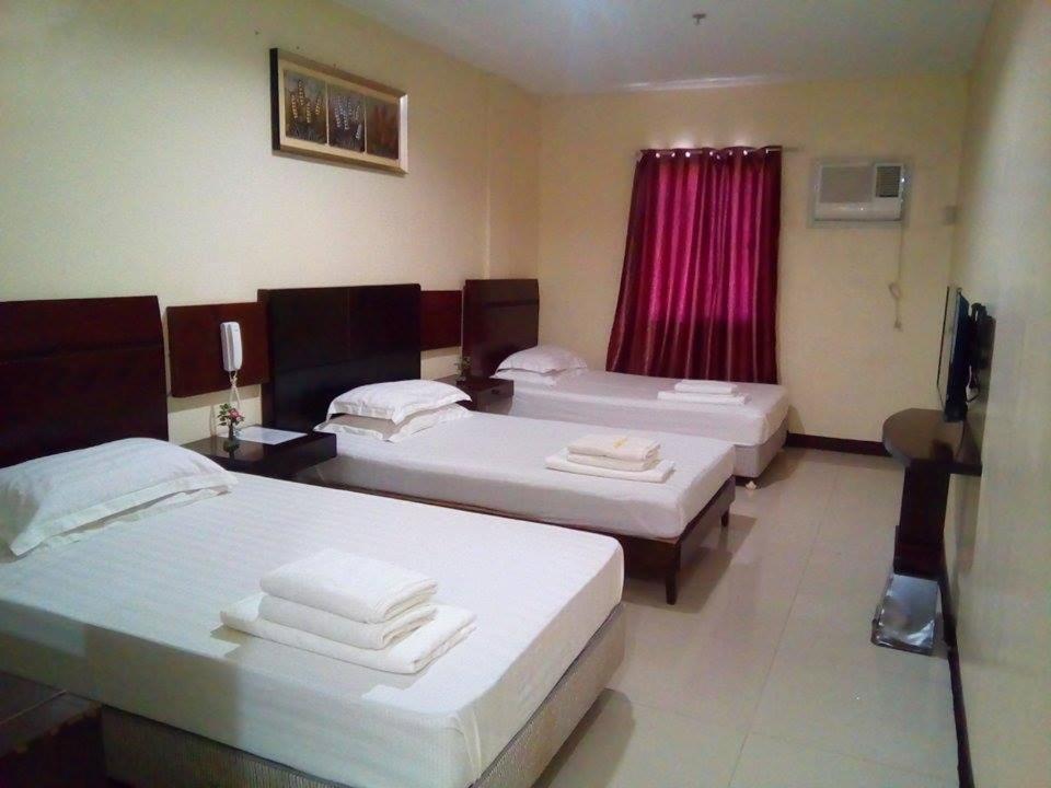 Habitación de hotel con 3 camas y TV en Asia Novo Boutique Hotel - Ozamis, en Ozamis