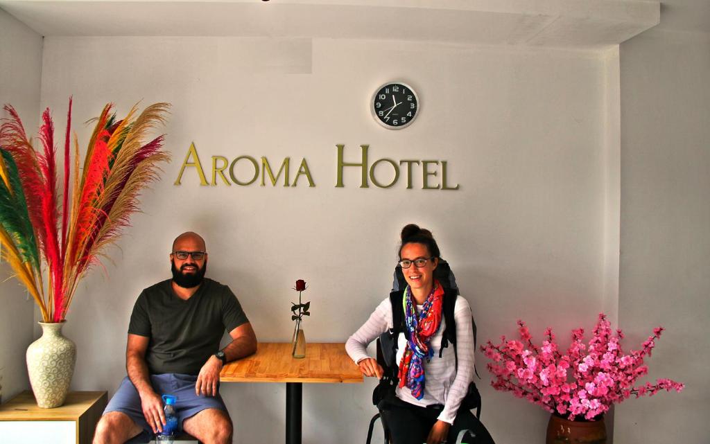 Sapa Aroma Hotel في سابا: يجلس رجل وامرأة على طاولة أمام فندق رائحة