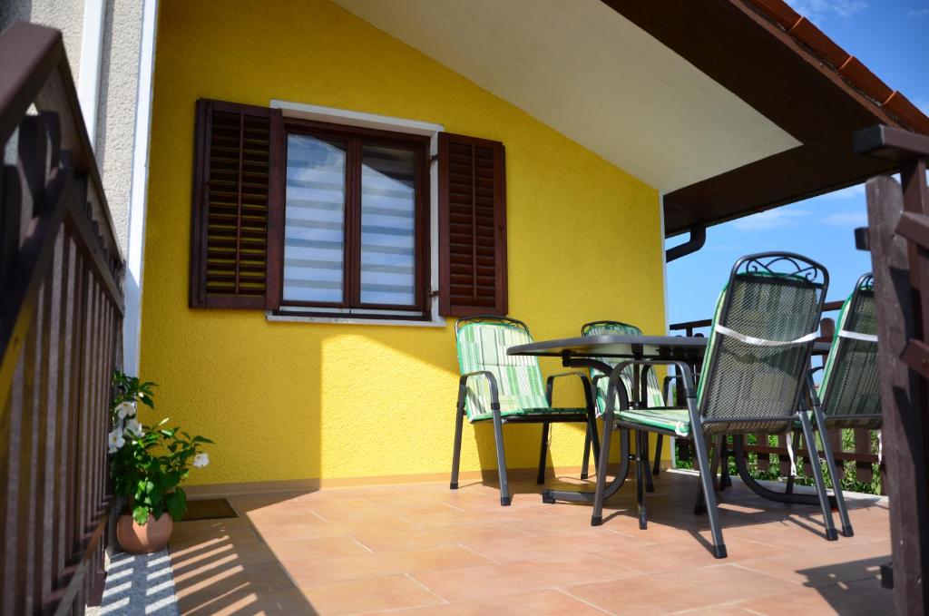 a patio with chairs and a table and a yellow wall at Apartma Louis in Dutovlje