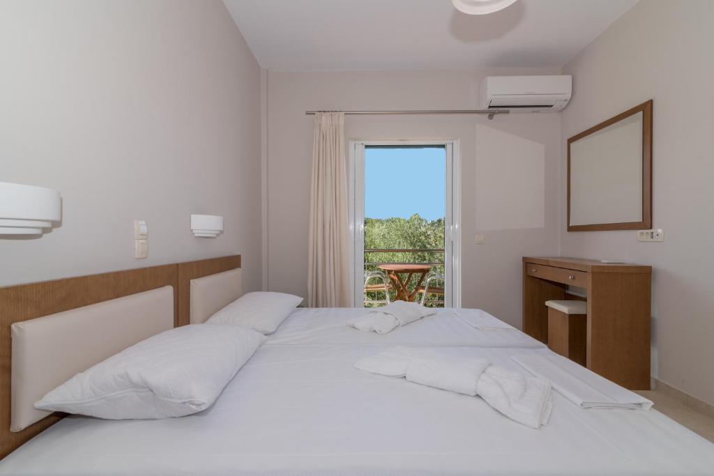 biała sypialnia z łóżkiem i oknem w obiekcie Allegro Studios & Apartments w mieście Marathias
