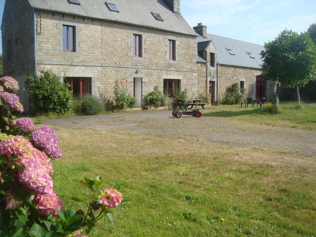 une grande maison en pierre avec une brouette devant elle dans l'établissement Kerbave Braz, à Plouzélambre