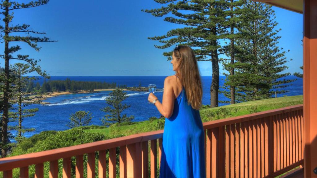 Una mujer parada en un balcón con vistas al agua en Shearwater Scenic Villas, en Burnt Pine