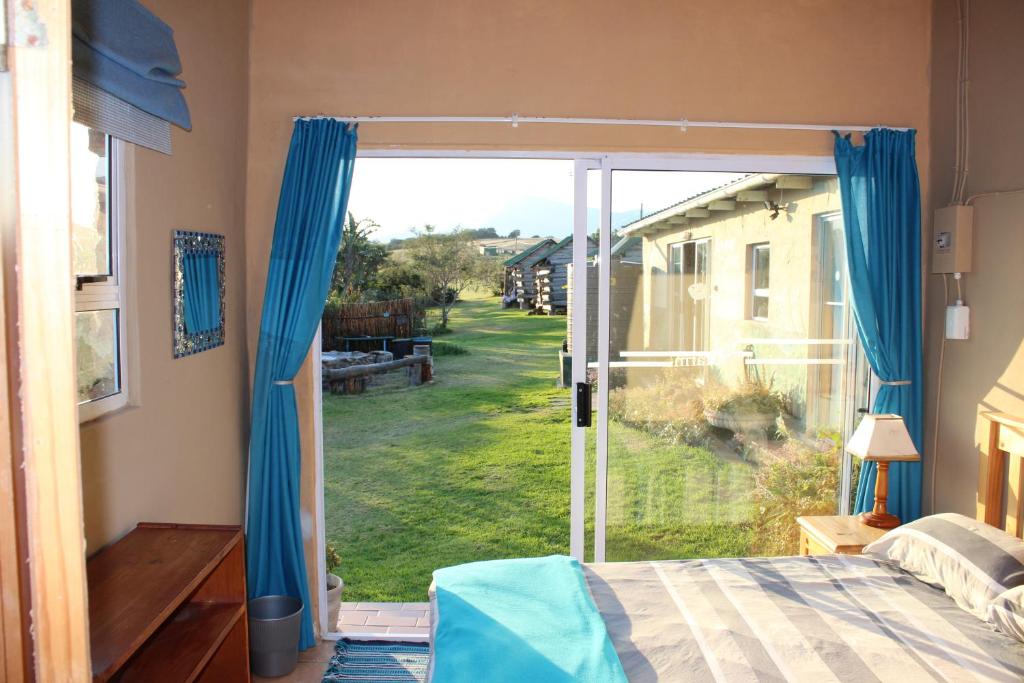 a bedroom with a door open to a yard at The Wild Farm Backpackers in Wilderness