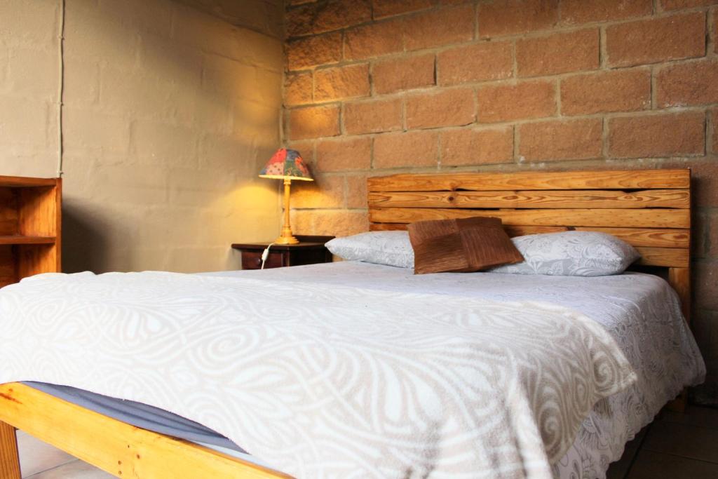 a bedroom with a large bed with a brick wall at The Wild Farm Backpackers in Wilderness