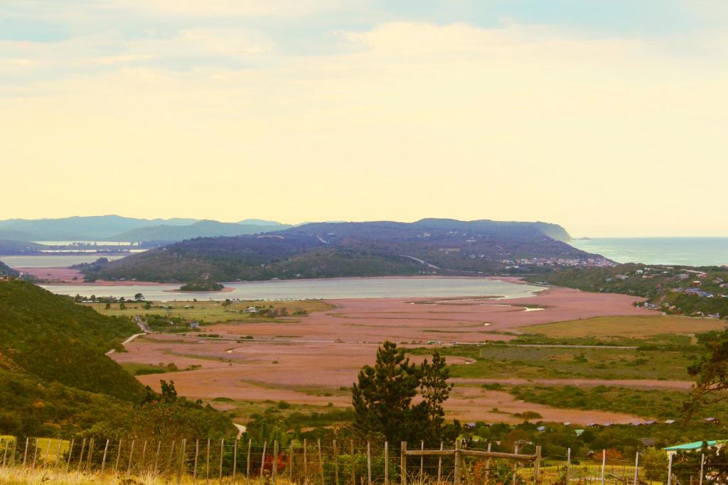 a view of a field with the ocean and mountains at The Wild Farm Backpackers in Wilderness