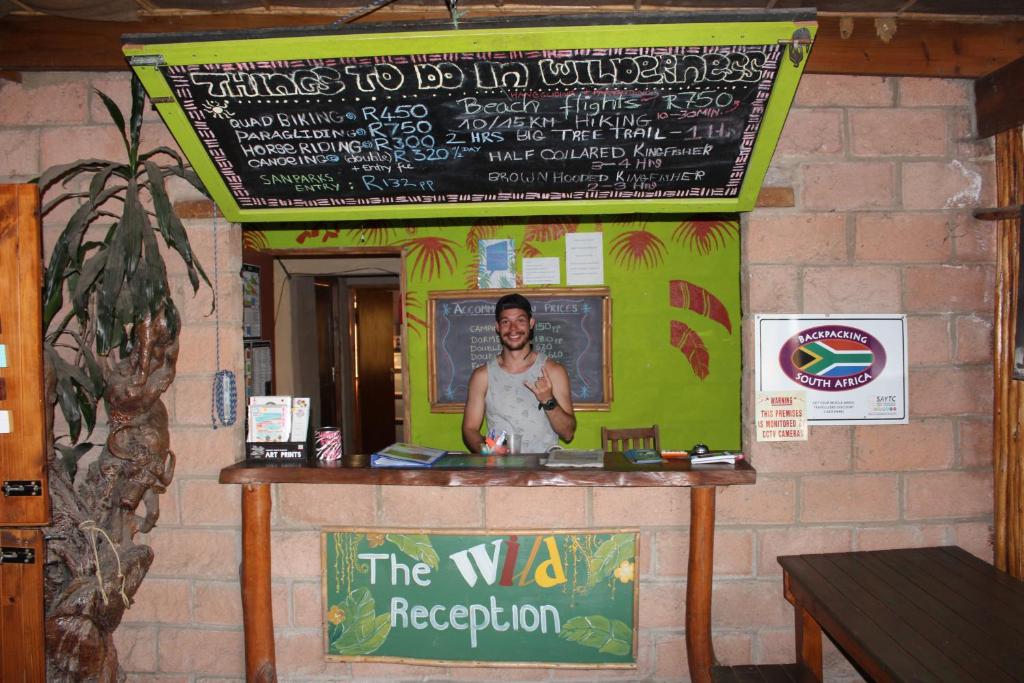 a man standing at a counter in a restaurant at The Wild Farm Backpackers in Wilderness