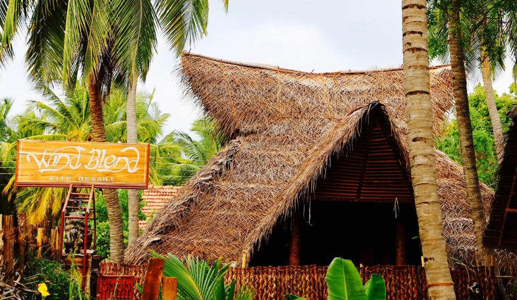 卡佩蹄尤的住宿－Wind Blend Kite Resort，一间拥有稻草标志和棕榈树的餐厅