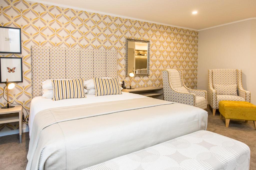 a hotel room with two beds and two chairs at ASURE Destiny on Fitzherbert Motel in Palmerston North