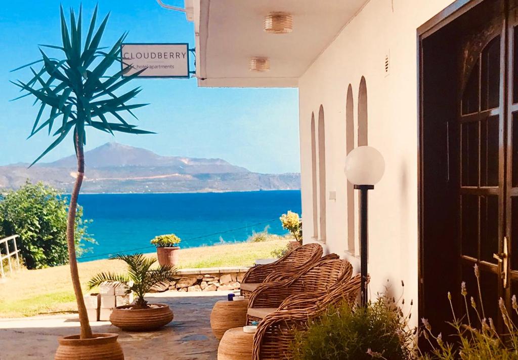 un groupe de chaises assises sur une terrasse couverte avec un palmier dans l'établissement Cloudberry, à Kalyves