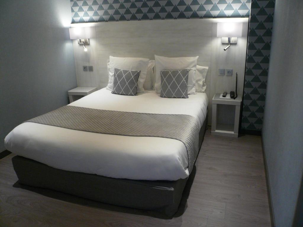 a bedroom with a large bed with white sheets and pillows at Hôtel L'Européen in Tarbes