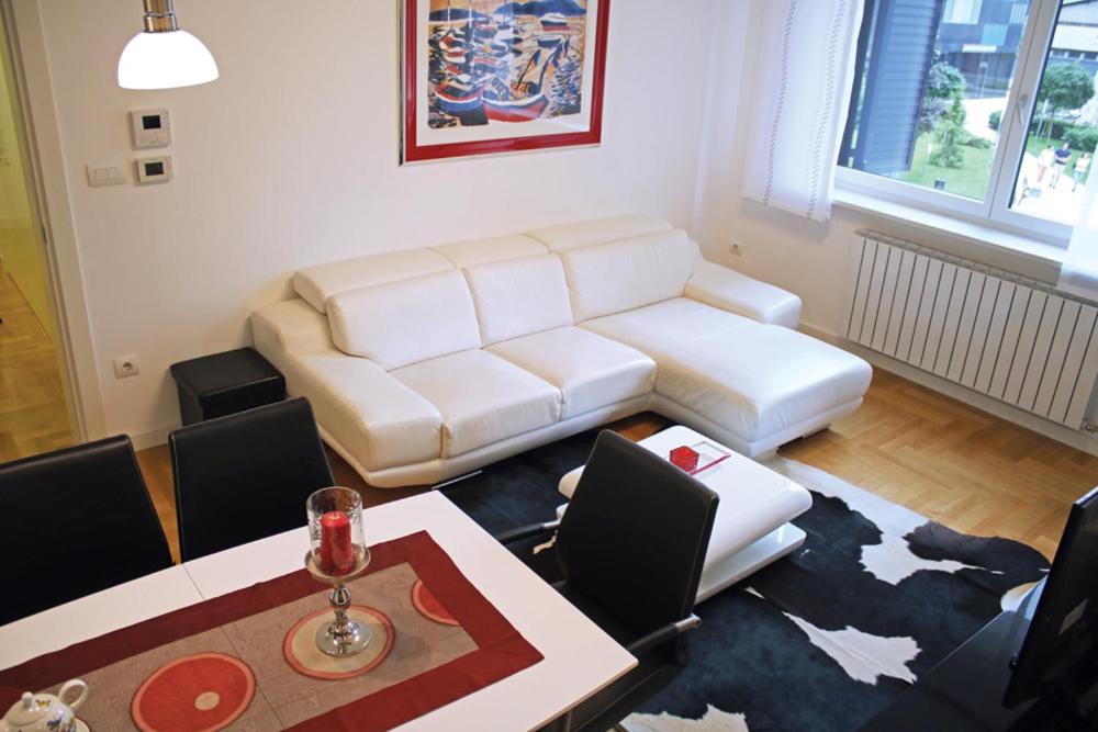 uma sala de estar com um sofá branco e uma mesa e cadeiras em Green Diamond em Zagreb
