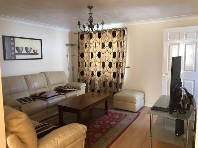 ein Wohnzimmer mit einem Sofa und einem Tisch in der Unterkunft Spacious 3-Bedroom Home in Colchester