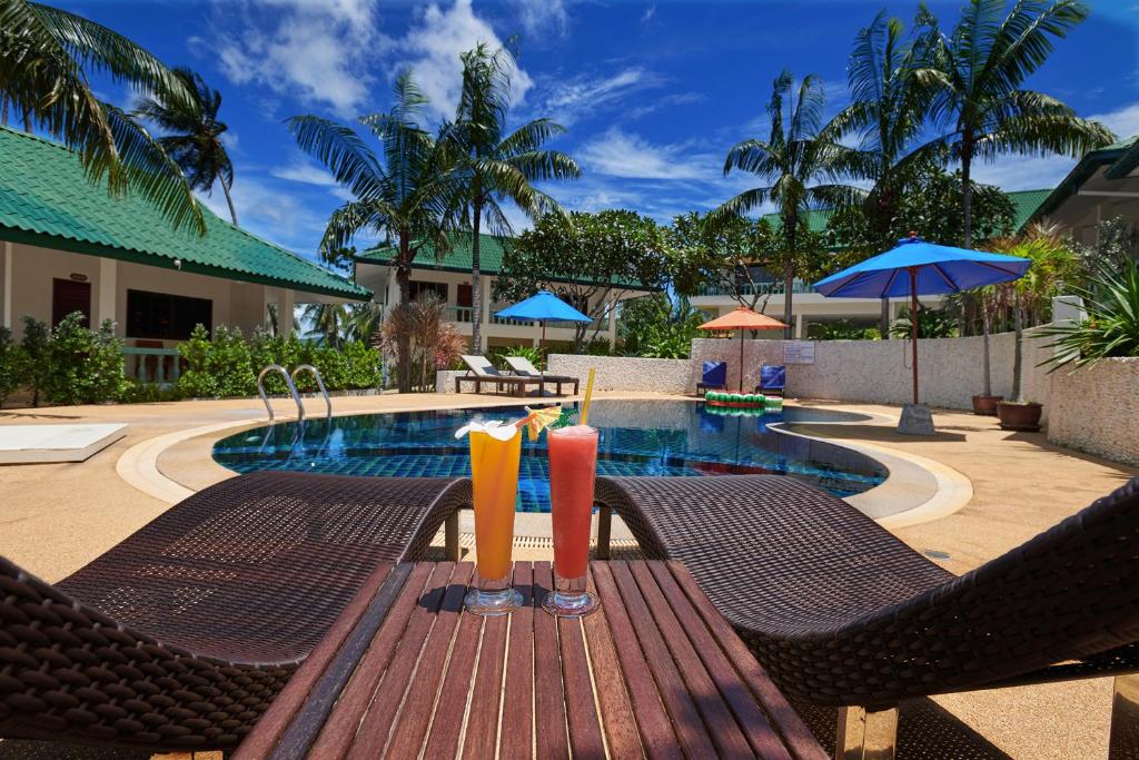 two drinks on a wooden table next to a pool at Samui Reef View Resort in Lamai