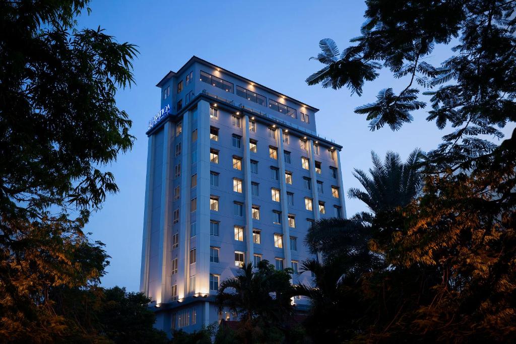 a tall building with lights on it at night at BATIQA Hotel Darmo - Surabaya in Surabaya