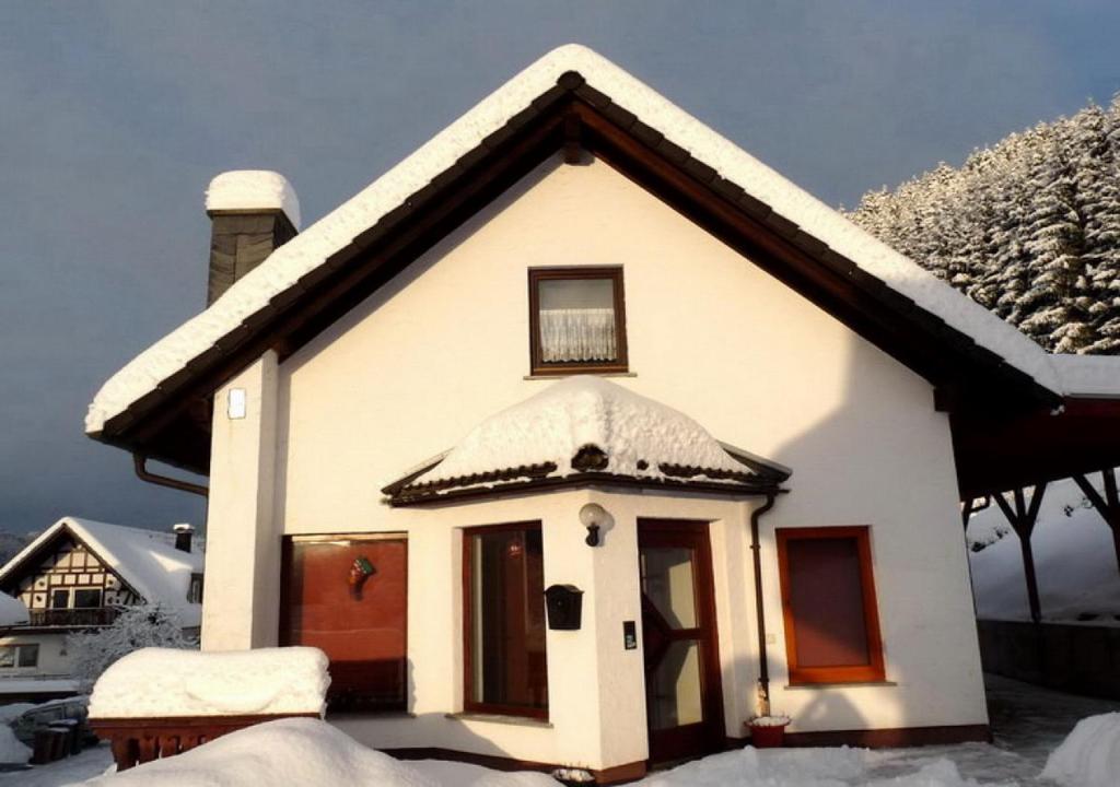 ein kleines weißes Haus mit Schnee auf dem Dach in der Unterkunft Ferienhaus Rothaargebirge in Bad Berleburg
