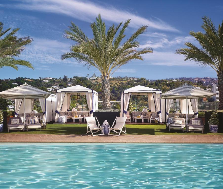 洛杉磯的住宿－比佛利山莊倫敦西好萊塢酒店，一个带椅子的度假村和一个棕榈树游泳池