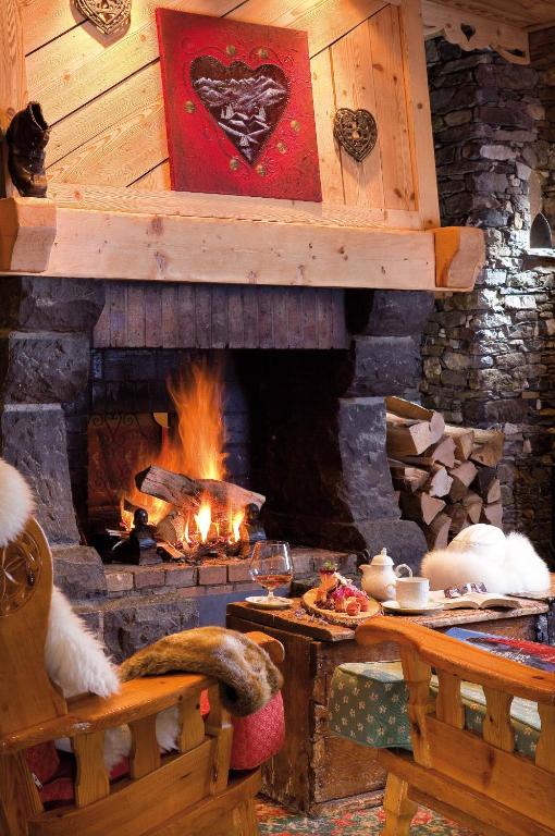 a living room with a stone fireplace and a table at Hôtel Le Sherpa Val Thorens in Val Thorens