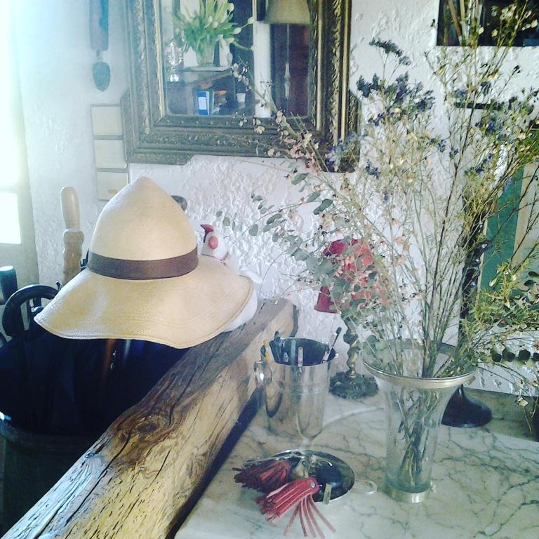 a person wearing a straw hat sitting on a counter at Les Hotes Des Guillemets in Laglorieuse