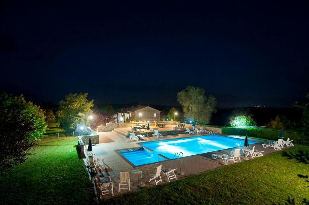una piscina por la noche con sillas alrededor en Agriturismo Cerqueto, en Acquapendente