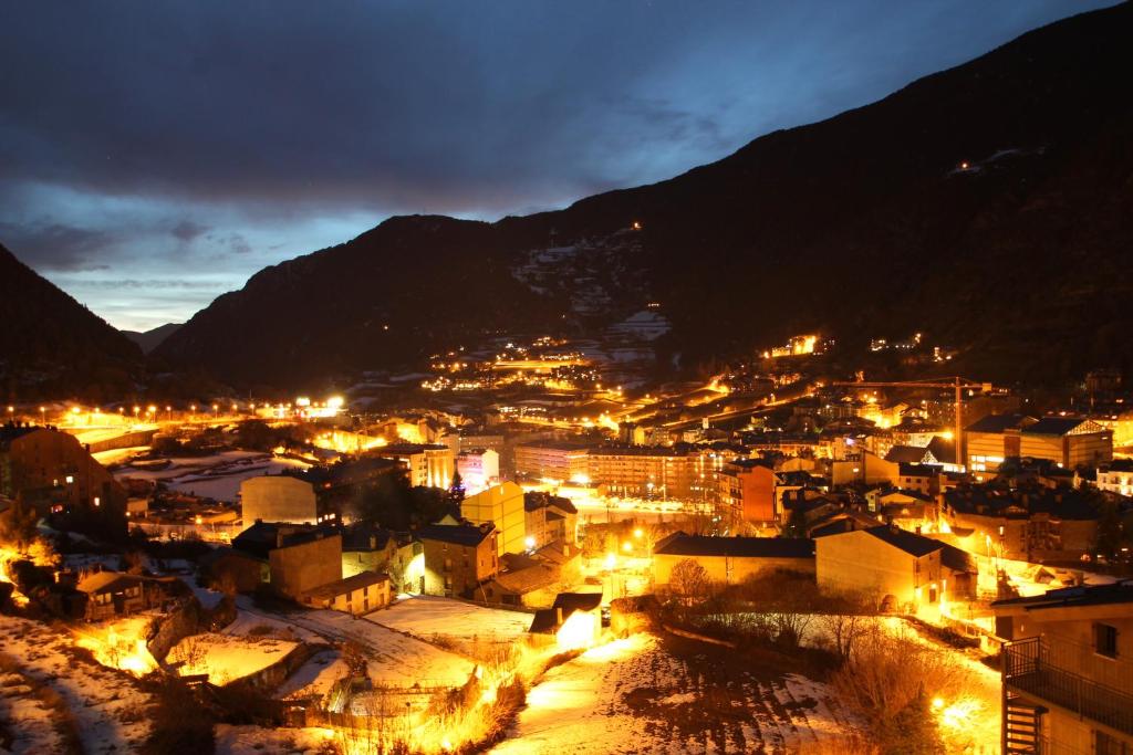 une ville éclairée la nuit avec des montagnes en arrière-plan dans l'établissement Prat del Tirader, Atico en Encamp, Zona Grandvalira, à Encamp