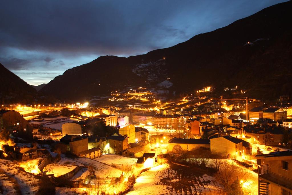 una città illuminata di notte con montagne sullo sfondo di Prat del Tirader, Atico en Encamp, Zona Grandvalira a Encamp