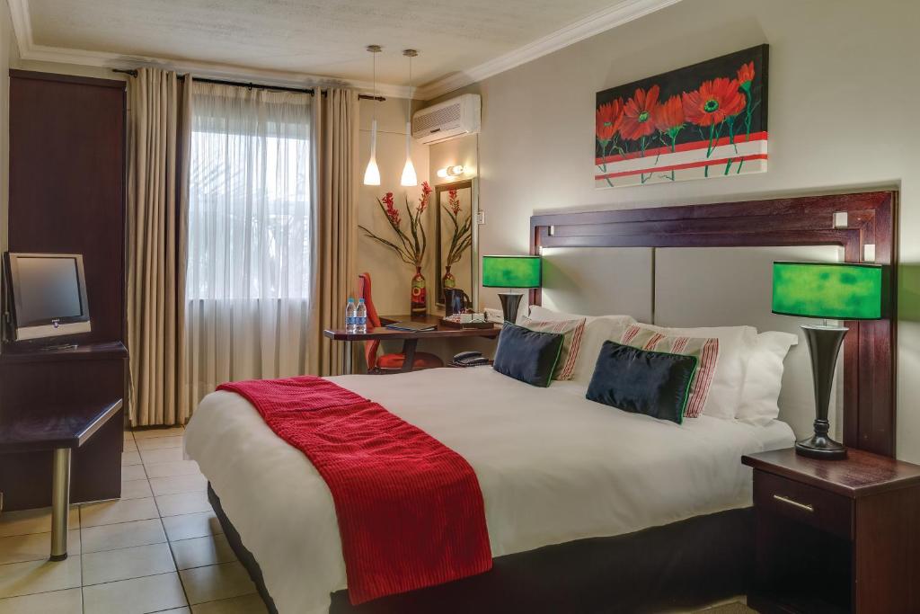 um quarto de hotel com uma cama grande e uma televisão em BON Hotel Empangeni em Empangeni