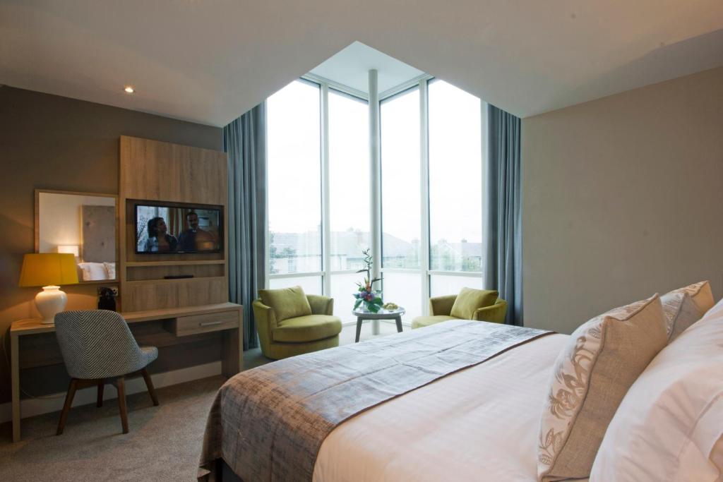 a bedroom with a large bed and a large window at Gleesons Townhouse Booterstown in Dublin