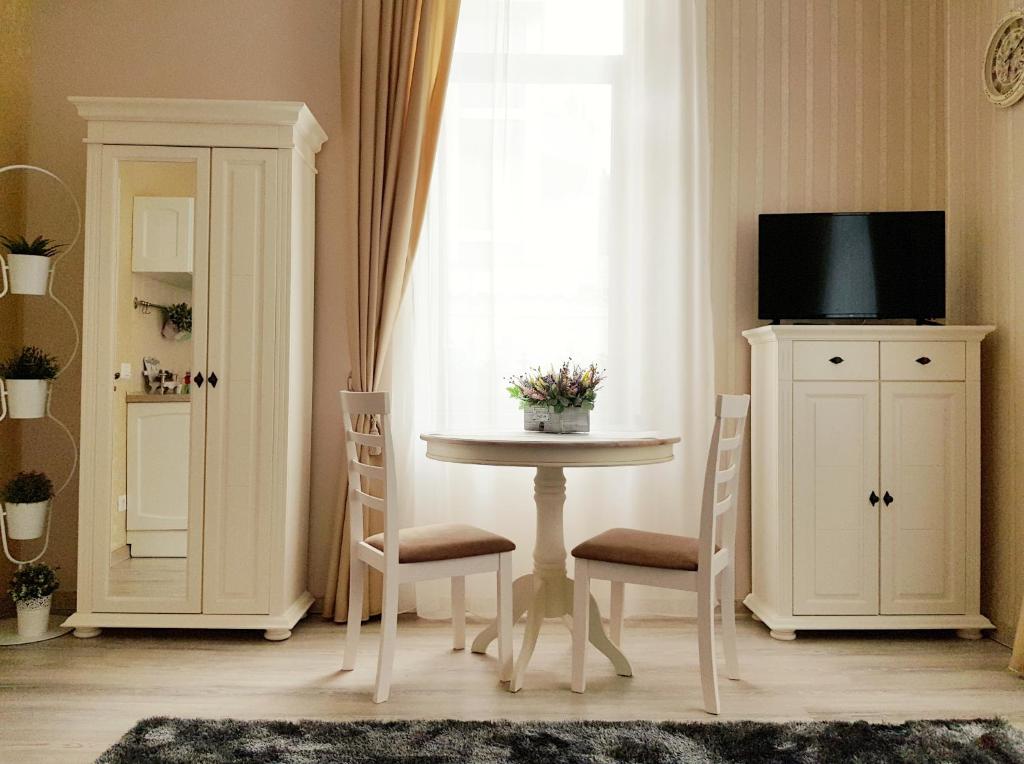 una sala da pranzo con tavolo, sedie e TV di Adagio Residence a Constanţa