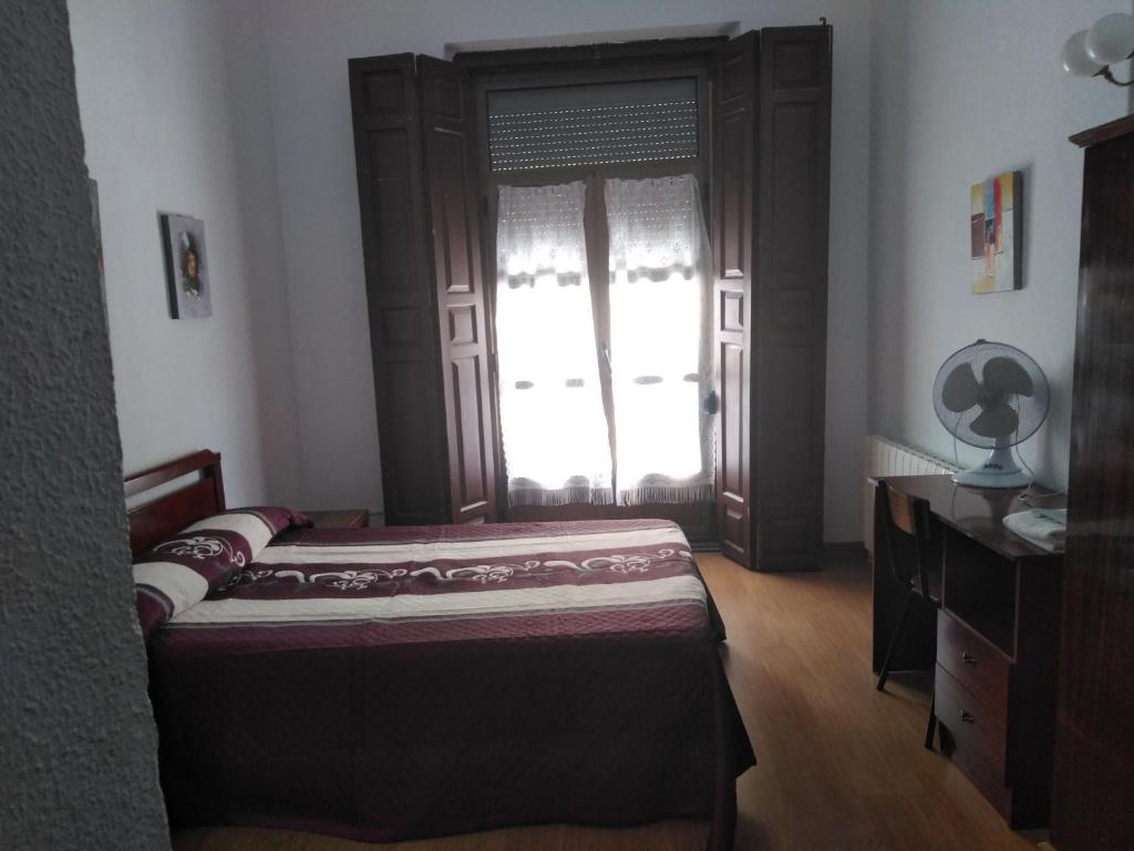 a bedroom with a bed and a dresser and a window at Pension Carretero in Cáceres