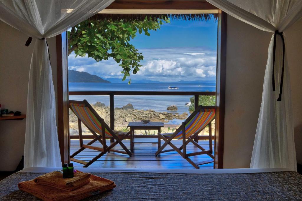 Coco Komba Lodge في Nosy Komba: غرفة بها كرسيين ومطلة على المحيط