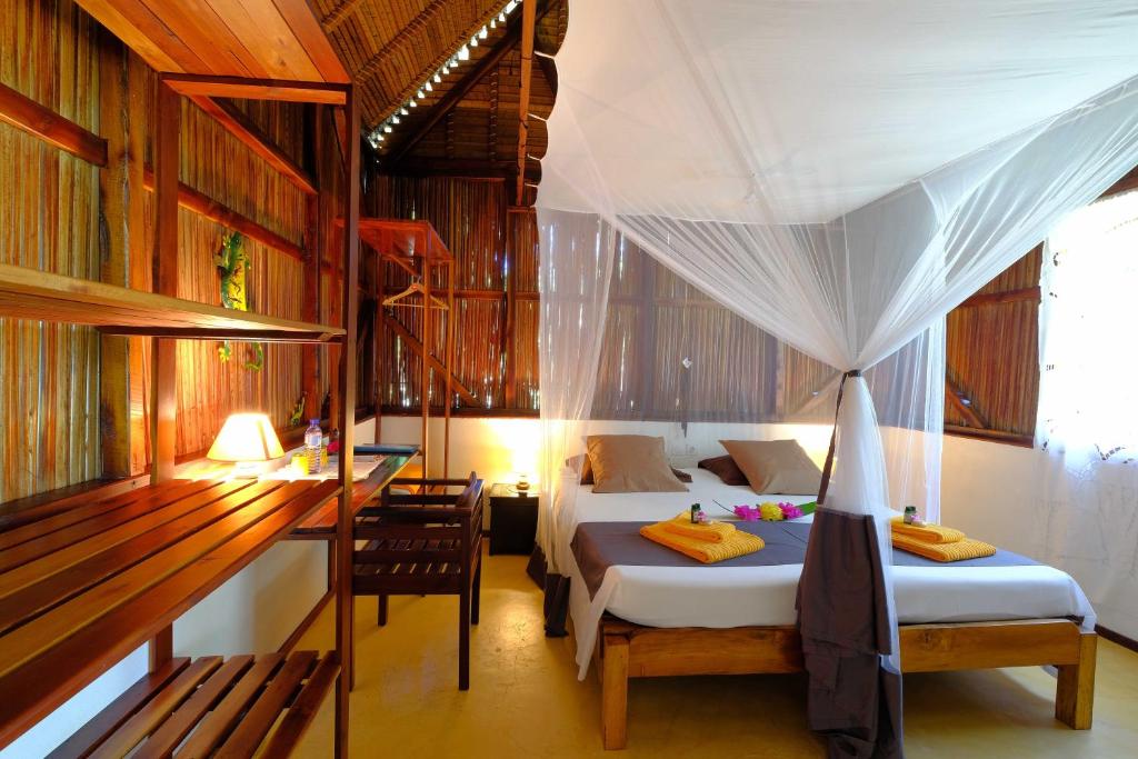 a bedroom with two beds and a desk and a table at Coco Komba Lodge in Nosy Komba