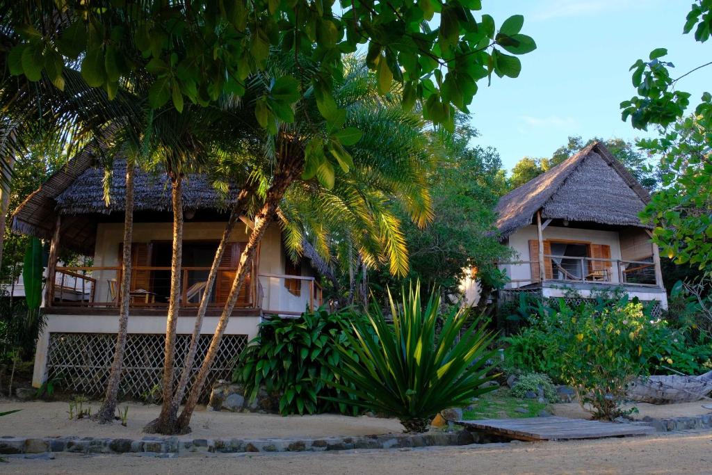 a house with palm trees in front of it at Coco Komba Lodge in Nosy Komba