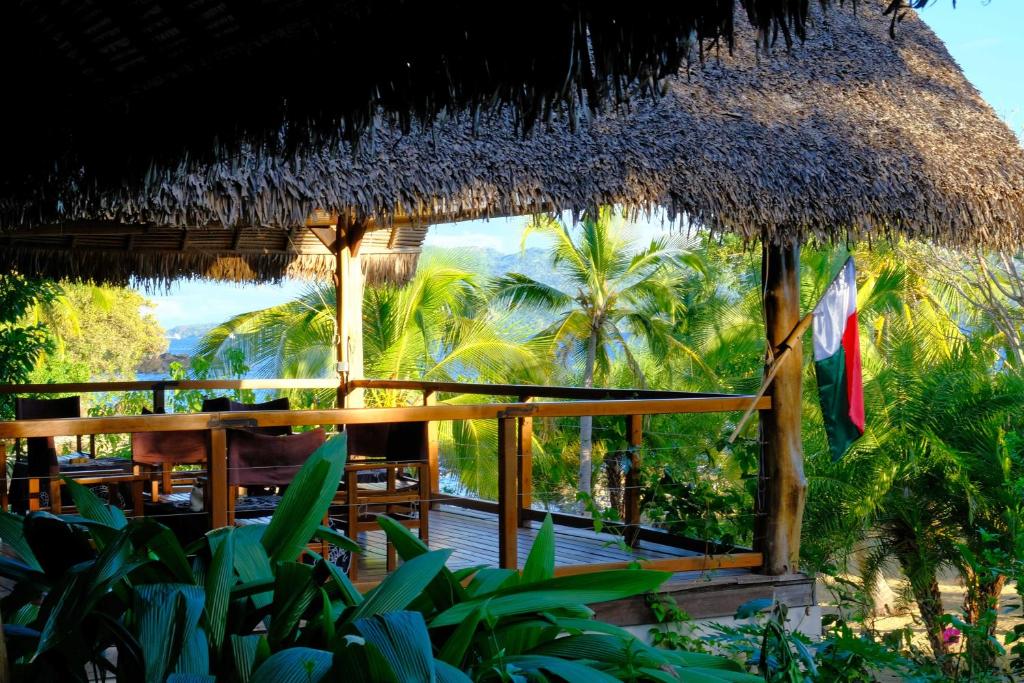 a straw hut with a deck and palm trees at Coco Komba Lodge in Nosy Komba