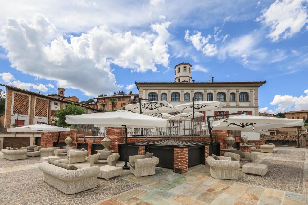 um pátio com cadeiras e guarda-sóis em frente a um edifício em Relais Villa Prato em Mombaruzzo