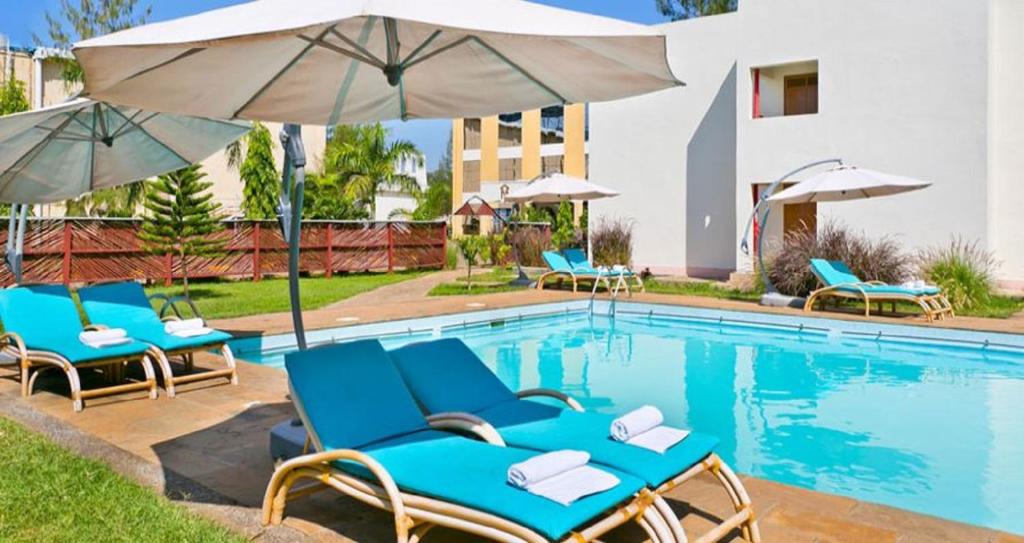 una piscina con sillas y sombrillas azules en The Vic Hotel en Kisumu
