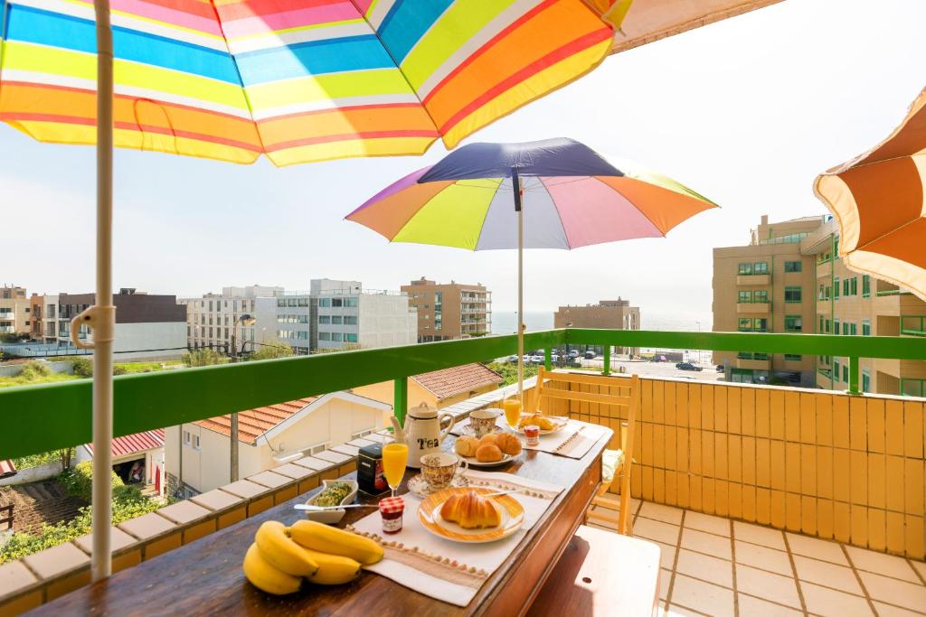 un balcone con tavolo, cibo e ombrellone di Oporto Beach Charm a Canidelo