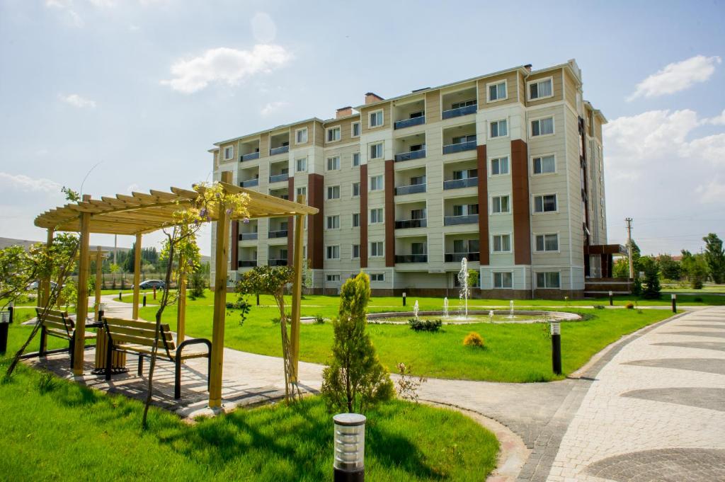 a building in a park with a bench and a building at Aforia Thermal Residences in Afyon