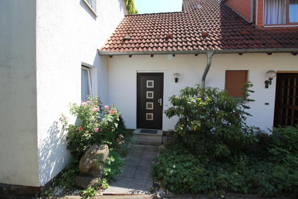 a white house with a black door and some flowers at Apartment Nada in Kassel