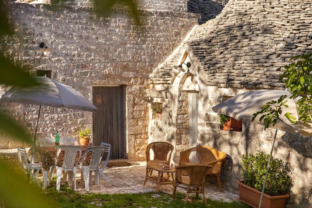 ロコロトンドにあるTrulli e Masseria Ianellaのパティオ(テーブル、椅子、パラソル付)