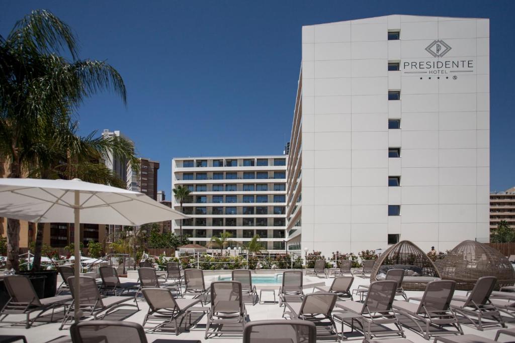 basen z krzesłami i parasolem oraz budynek w obiekcie Hotel Presidente 4 sup w mieście Benidorm