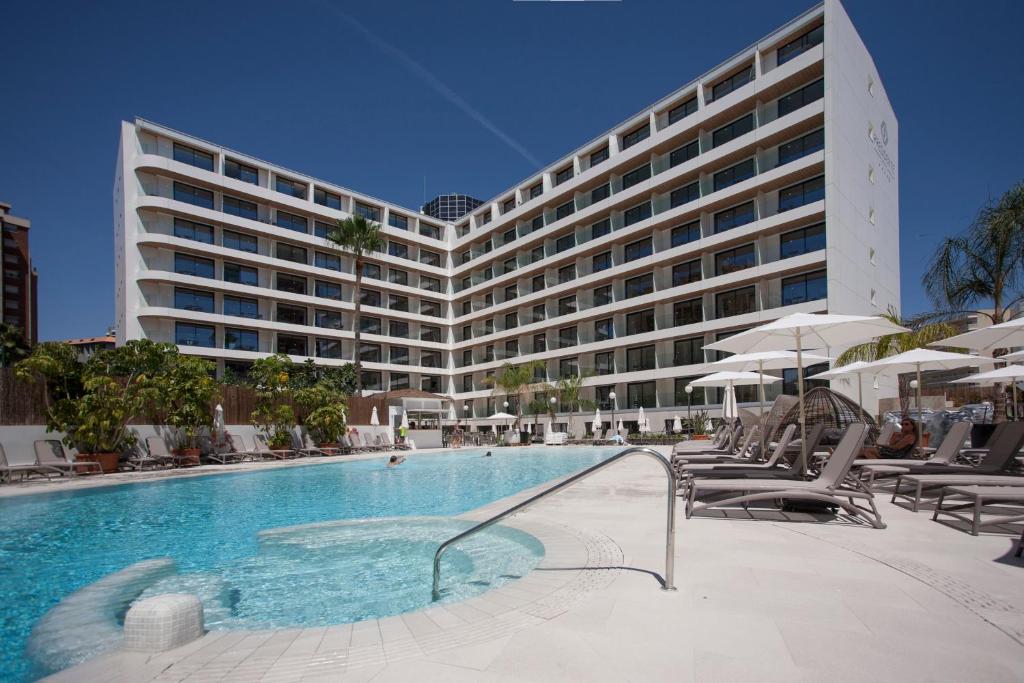 uma piscina de hotel com um grande edifício ao fundo em Hotel Presidente 4 sup em Benidorm